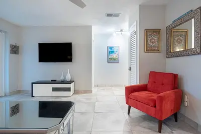 a living room with a red chair and a tv at Wilton Manors 2BR Bungalow, Private Pool, Sleeps 6 in Fort Lauderdale