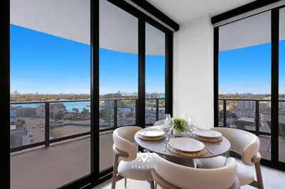 a dining room with a table and chairs and large windows at Chic 2BR Apartment Gym & Balcony Views in Miami Beach