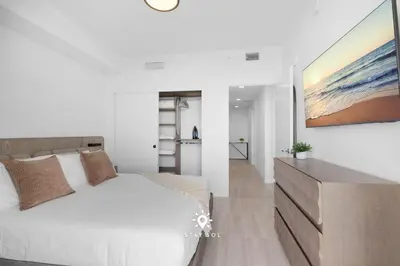 a bedroom with a white bed and a painting on the wall at Chic 2BR Apartment Gym & Balcony Views in Miami Beach