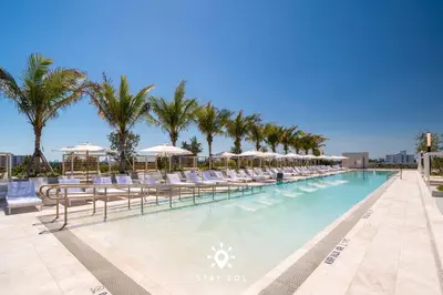 a pool with chairs and umbrellas and palm trees at Beautiful Apt -Private Balcony & Pool in Miami Beach