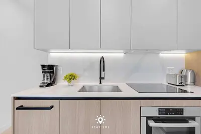 a kitchen with white cabinets and a sink at Coastal Apartment - Pool & Breezy Balcony in Miami Beach