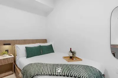 a bedroom with a white bed with green pillows at Coastal Apartment - Pool & Breezy Balcony in Miami Beach