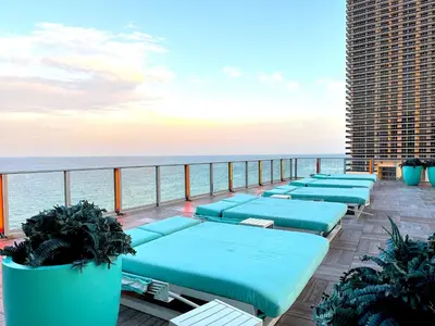 a row of blue chaise lounges on a balcony overlooking the ocean at Lyfe Resort & Residences in Hollywood