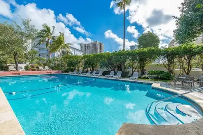a large swimming pool with chairs and trees at South Beach Paradise Jr Suite next to Convention Center in Miami Beach