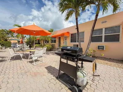 a bbq grill with chairs and a table with an umbrella at Exclusive studio steps to the beach with pool in Hollywood
