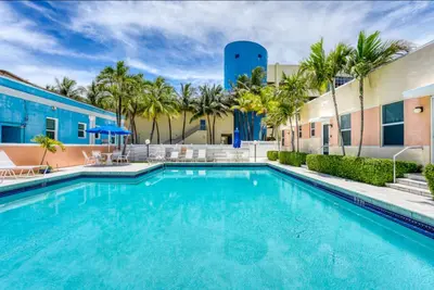 a swimming pool in front of a building with palm trees at Exclusive studio steps to the beach with pool in Hollywood
