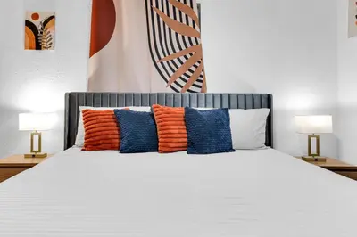 a bed with orange and blue pillows and two lamps at Prized by Florida |Private Pool and HotTub Oasis| in Fort Lauderdale
