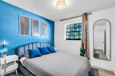 a bedroom with a bed with blue walls and a mirror at Prized by Florida |Private Pool and HotTub Oasis| in Fort Lauderdale