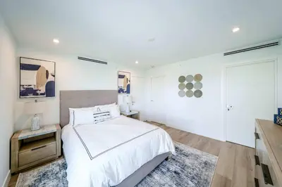 a white bedroom with a bed and a table at Bayview Villa by Rove Travel - Waterfront with Patio in Miami Beach