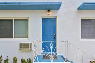 a blue door on a white house with a blue porch at Tropical Haven Cozy 1 BR Caribbean Getaway in Miami