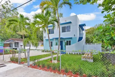 a house with palm trees in front of a fence at Tropical Haven Cozy 1 BR Caribbean Getaway in Miami