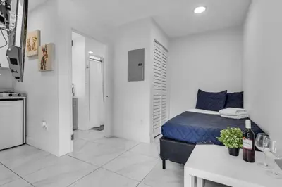 a white room with a bed and a kitchen at Tropical Haven Cozy 1 BR Caribbean Getaway in Miami