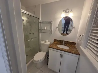 a person taking a picture of a bathroom with a toilet and shower at Modern Home in Hallandale Beach in Hallandale Beach