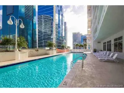 a large swimming pool with chairs and buildings at Stylish 1BR Modern Apt in Brickell - Free Parking in Miami