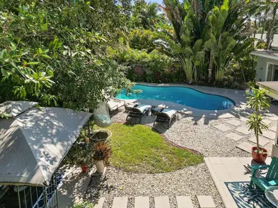 a backyard with a pool with chairs and a table at 3-Bedroom Villa with Heated Pool near Wilton Drive & Fort Lauderdale Beach in Fort Lauderdale