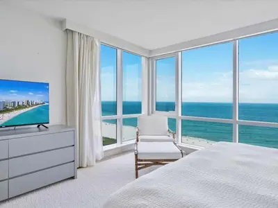 a bedroom with a bed and a television and the ocean at Villa Lumea in Miami Beach