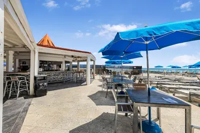 a patio with tables and umbrellas on the beach at Beachfront Studio with Resort Access STR-02630 in Sunny Isles Beach