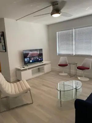 a living room with a tv and two chairs and a table at Beach Escape in Fort Lauderdale