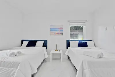 two beds in a white room with a window at Modern 2-Bedroom Apartment in Miami