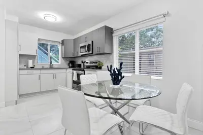 a kitchen with a glass table and white chairs at Modern 2-Bedroom Apartment in Miami