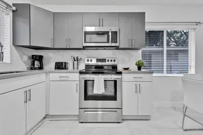a white kitchen with a stove and a microwave at Modern 2-Bedroom Apartment in Miami