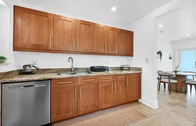 a kitchen with wooden cabinets and a stainless steel dishwasher at The Perfect South Florida Experience in Fort Lauderdale
