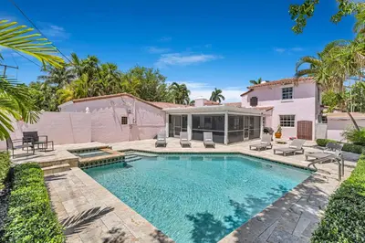 a swimming pool with chairs and a house at Stunning Tropical Getaway Steps To The Beach with Pool in Hollywood