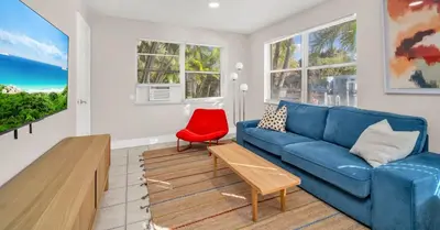 a living room with a blue couch and a red chair at The Jute Box - Pool - Waterview - Wilton Drive in Fort Lauderdale