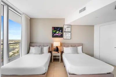 two beds in a room with two windows at Corner Penthouse Ocean and City View in Hollywood