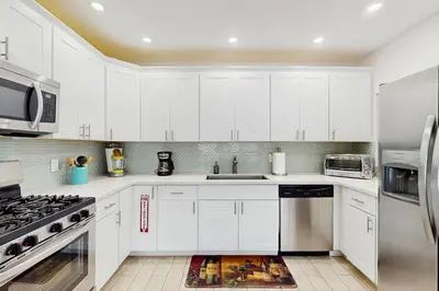 a kitchen with white cabinets and stainless steel appliances at The Front House in Fort Lauderdale