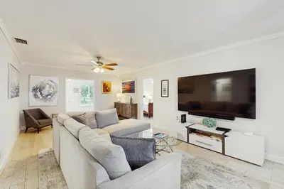 a living room with a couch and a large flat screen tv at The Front House & Cottage in Fort Lauderdale