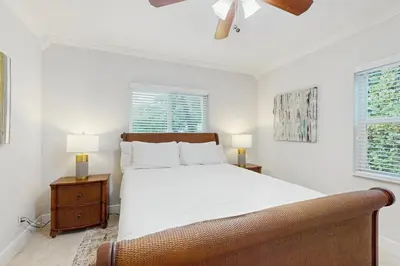 a white bedroom with a bed and two windows at The Front House & Cottage in Fort Lauderdale