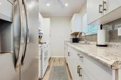 a kitchen with white cabinets and a stainless steel refrigerator at The Cottage in Fort Lauderdale