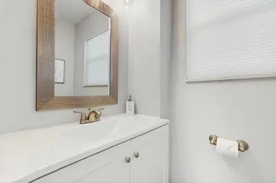 a white bathroom with a sink and a mirror at The Cottage in Fort Lauderdale