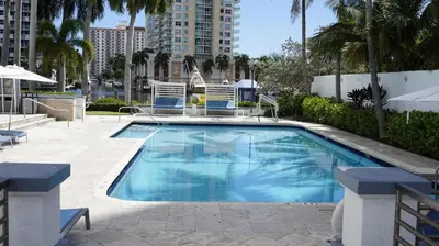 a swimming pool with two lawn chairs and palm trees at Sunrise on the Intracoastal in Fort Lauderdale
