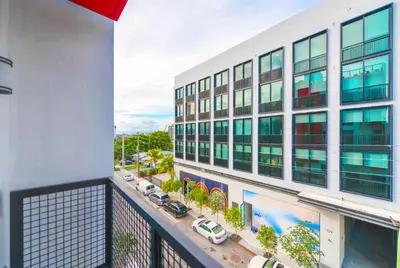 an apartment balcony with a white building and cars at Wynwood Retreat - Rooftop Pool & Neighborhood Views in Miami