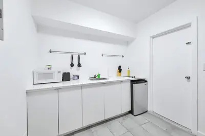 a white kitchen with white cabinets and a microwave at Modern Studio Retreat to Explore Miami in Miami