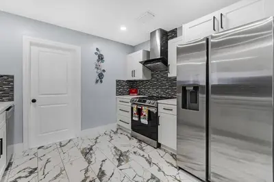a kitchen with a stainless steel refrigerator and white cabinets at RJ Home Away From Home LLC in Miami Gardens