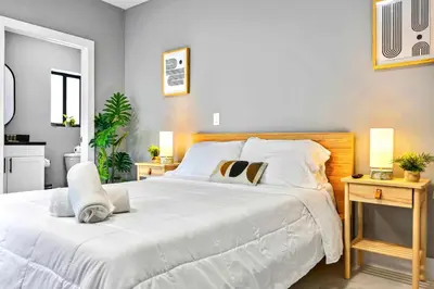 a bedroom with a large white bed with two tables at Central Miami Studio - Wynwood 8 Min in Miami