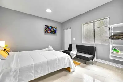 a bedroom with a white bed and a chair at Central Miami Studio - Wynwood 8 Min in Miami