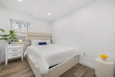 a white bedroom with a bed and a window at Cozy By The Blue in Miami