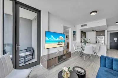 a living room with a blue couch and a tv at Miami City Lights 2BR 2BA in Miami