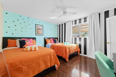 a bedroom with two beds with orange sheets at Large 12 Guest Home w Pool, Hollywood FL in Hollywood