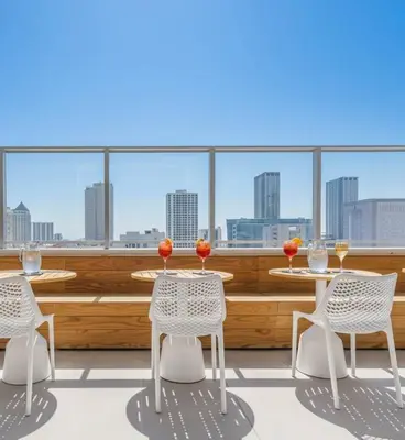 a balcony with tables and chairs and a view of the city at Skyline Nomad Studio Walk to Kaseya Rooftop Pool in Miami