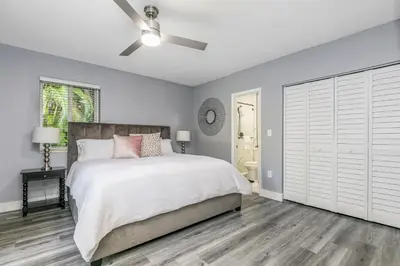 a white bedroom with a bed and a ceiling fan at Modern Miami Oasis with Pool & Water View in North Miami