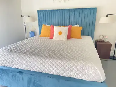 a large bed with a blue headboard and colorful pillows at Lux Villa Sol in Miami