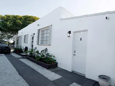 a white building with a door and some plants at Rio retreat - Unit B in Miami