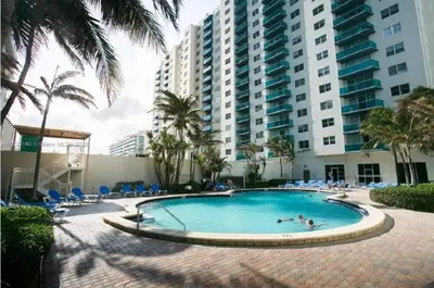 a swimming pool in front of a large building at Oceanview 3BR Penthouse | Pool + Beach Access in Hallandale Beach