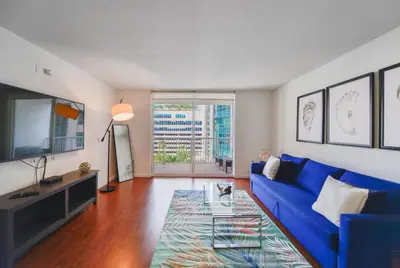 a living room with a blue couch and a tv at Luxury Suite | Sauna, Pool & Resort Access in Miami