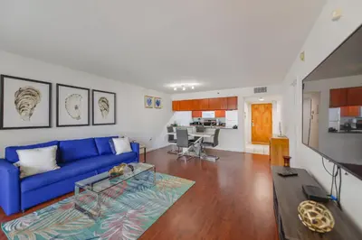 a living room with a blue couch and a kitchen at Luxury Suite | Sauna, Pool & Resort Access in Miami